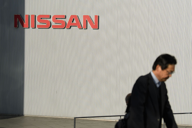 A pedestrian walks past a logo at the Nissan Motor Co. headquarters in Yokohama, Japan, on Thursday, Feb. 13, 2020.