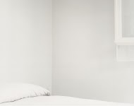 wit opgemaakt bed in witte kamer