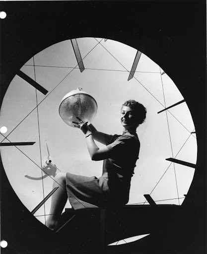 Judy Rowe holds one of new street lights on her knees inside a giant, light testing "hemisphere" at the General Electric Company's Illuminating Laboratory in Lynn, Mass. The fixtures were developed and tested at the laboratory before being installed. The "Hemisphere," like the iris diaphragm of a camera, can be closed down to a pinpoint to meet specific needs in light testing streets and floodlights.