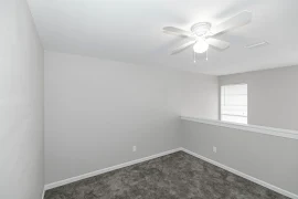 Loft bedroom with ceiling fan and light, grey walls and carpet, white trim