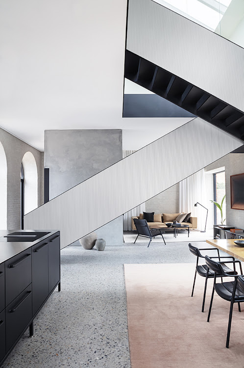 A steel staircase separates the dining and living areas.