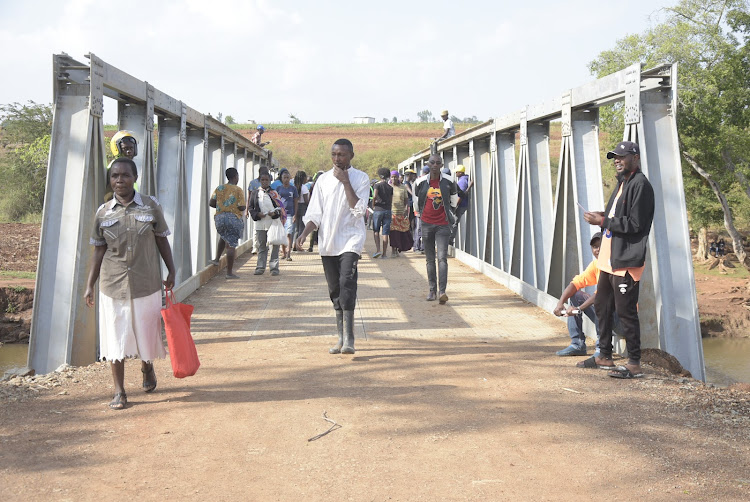 Residents cross Thika River using the newly constructed bridge on Wednesday.