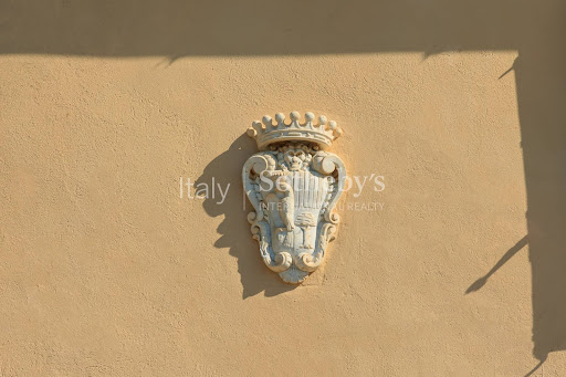 sculpted coat of arms on ochre exterior wall - Luxury villa for sale in Castagneto Carducci, 26 rooms, 8 bedrooms