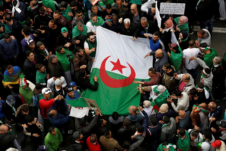 Demonstrators hold flags and banners as they return to the streets to press demands for wholesale democratic change well beyond former president Abdelaziz Bouteflika's resignation in Algiers on April 19, 2019