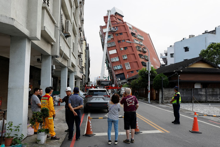 People look on as workers carry out operations while on an elevated platform of a firefighting truck at the site where a building tipped, following the earthquake, in Hualien, Taiwan, April 4 2024. Picture: REUTERS/Carlos Garcia Rawlins