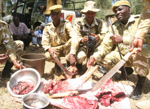 KWS officers examine game meat and snares recovered from three suspects in Naivasha