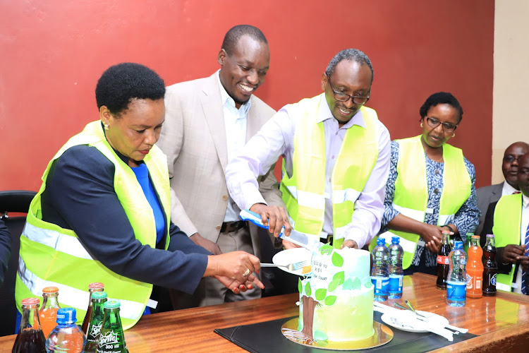 Justice Sila Munyao cuts a cake to mark 10 years since the establishment of the lands and environment court as Kisii Governor Simba Arati looks on.