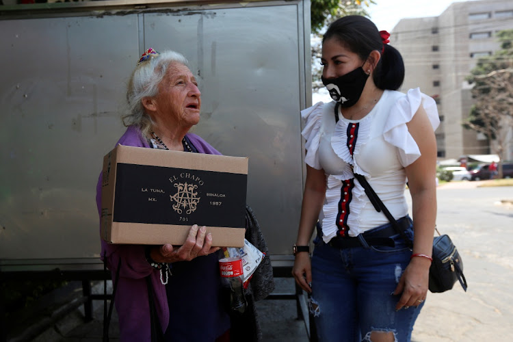 An employee of the clothing brand "El Chapo 701", owned by Alejandrina Gisselle Guzman, daughter of the convicted drug kingpin Joaquin "El Chapo" Guzman, speaks to an elderly woman after handing out a box with food, face masks and hand sanitizer as part of a campaign to help cash-strapped elderly people during the coronavirus disease (COVID-19) outbreak, in Guadalajara, Mexico April 16, 2020. The number 701 refers to the 2009 World's Billionaires ranking given by Forbes magazine to Mexican drug lord Joaquin "El Chapo" Guzman.