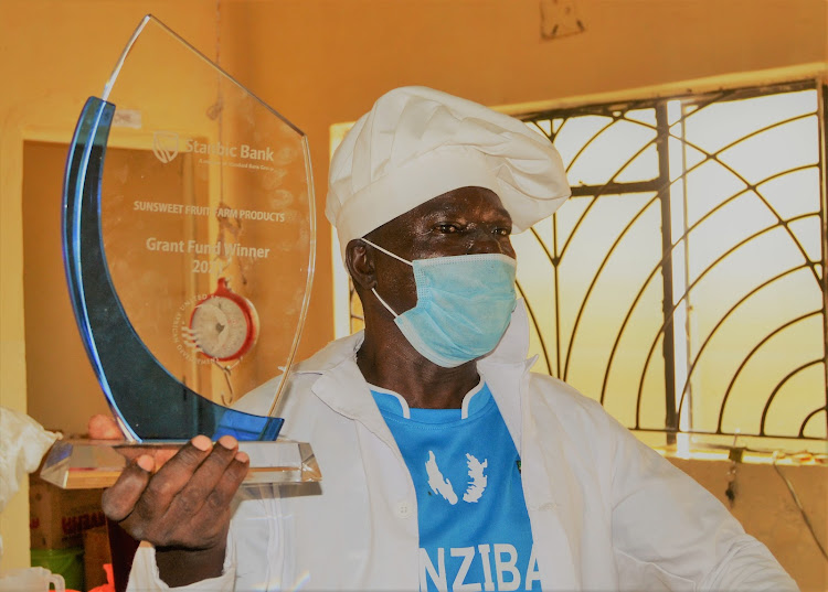 The proprietor Sun Sweet Fruit Farm Products in Kitui Simon Musyoka show the trophy he was awarded for winning the Stanbic Bank/USADF Sh. 3 million grant.