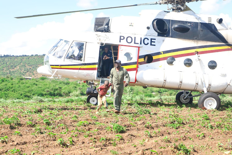 The National Police Service (NPS) Airwing Officer walks five-year-old Mutuku Kioko after he marooned by floods at Nduani in Yatta, Machakos County on April 23, 2024.