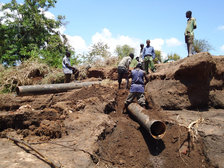 Workers repair a section of the Kiambere-Mwingi water pipeline that was damaged during heavy flooding by Kamuwongo seasonal river in Kyuso district, Kitui county.