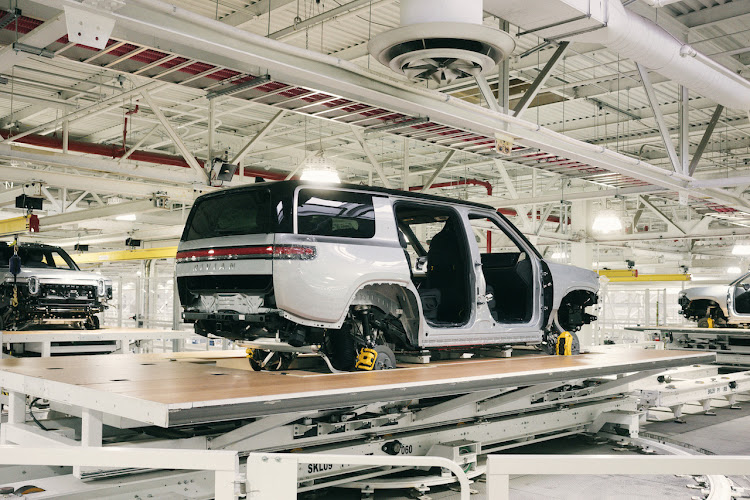 Rivian R1S SUVs being transferred between stations on the trim line in general assembly.