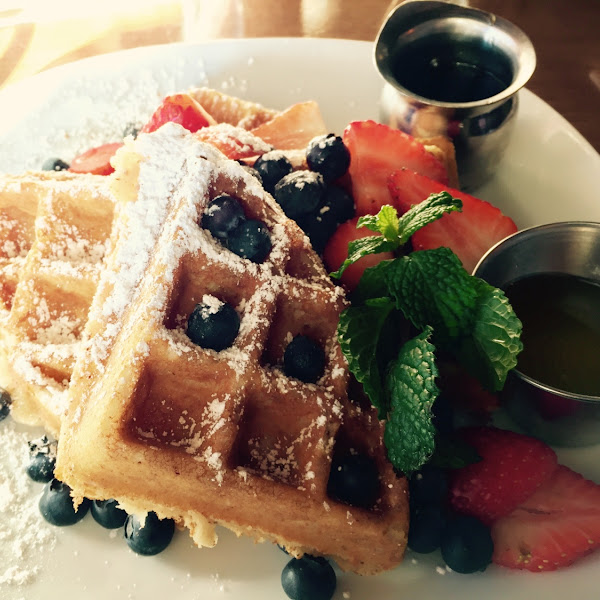 Gluten Free waffles with strawberries and blueberries, powdered sugar and syrup.