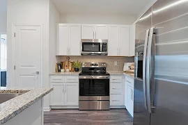 Modern kitchen in an apartment with white cabinets, stainless steel appliances, and a tiled backsplash.