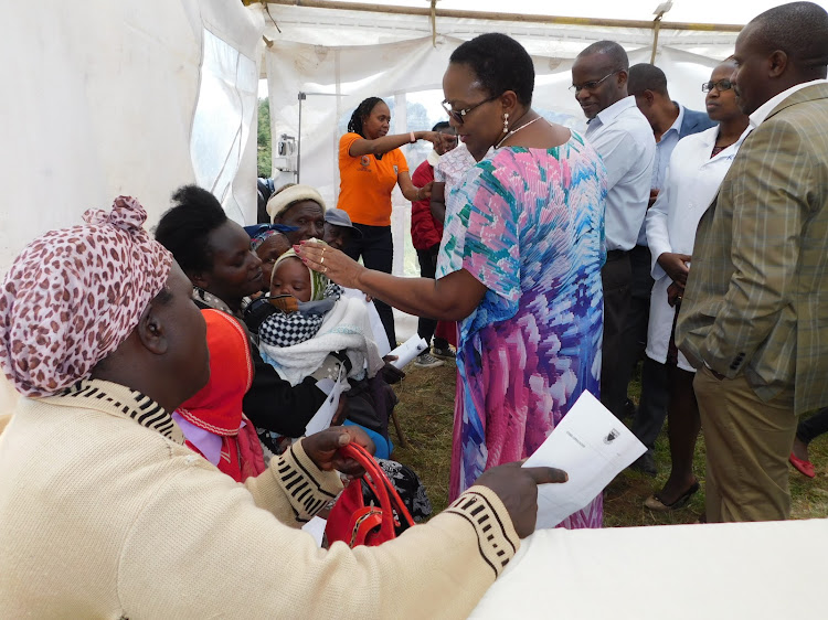 Outgoing Health CS Sicily Kariuki and Dr Menge from KNH interact with patients during a medical outreach at Tumaini Health Centre, Ol Kalou, on Friday