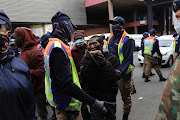 A person is questioned and released as police and soldiers move through Alexandra in Johannesburg. 