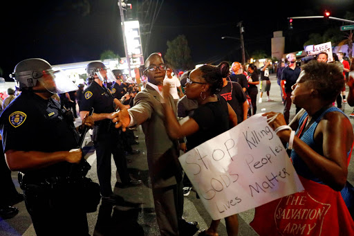 A man tries to diffuse tensions between protesters and police officers as people protest the death of Alfred Olango, who was shot by El Cajon police Tuesday, by blocking traffic near the parking lot where Olango was shot in El Cajon, California, U.S. September 29, 2016. REUTERS/Patrick T. Fallon