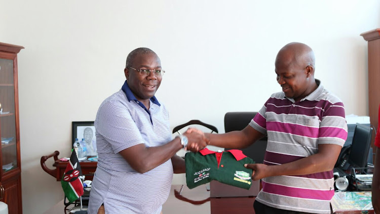 Metric Mukhalasie Defending Champion presenting Scrabble T-shirt and Board to His Excellency Deputy Governor Kisumu County Dr Owili.