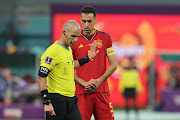 Referee Victor Gomes of South Africa brushes away Sergio Busquets of Spain while he waits for communication from the VAR prior to validate Ao Tanaka's goal to give Japan a 2-1 lead in the 2022 World Cup Group E match at Khalifa International Stadium in Doha, Qatar on December 1 2022.