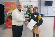 Mi7 marketing manager Ashley White hands over the money raised to help fund Siphokazi Dlamini's trip to Dubai, where she will participate in the International Spelling Bee.