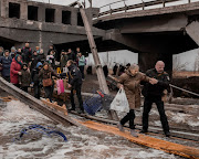 Local residents cross a destroyed bridge as they leave their town in Irpin, near Kyiv, Ukraine.