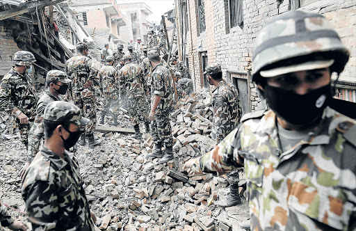 GRIM AFTERMATH: A team of soldiers clear rubble from a destroyed structure as they continue with search and recovery operations near Bhaktapurl, in Kathmandu, Nepal, yesterday. The death toll following the devastating earthquake last Friday is now well past the 4000 figure mark, with many thousands still missing Picture: EPA