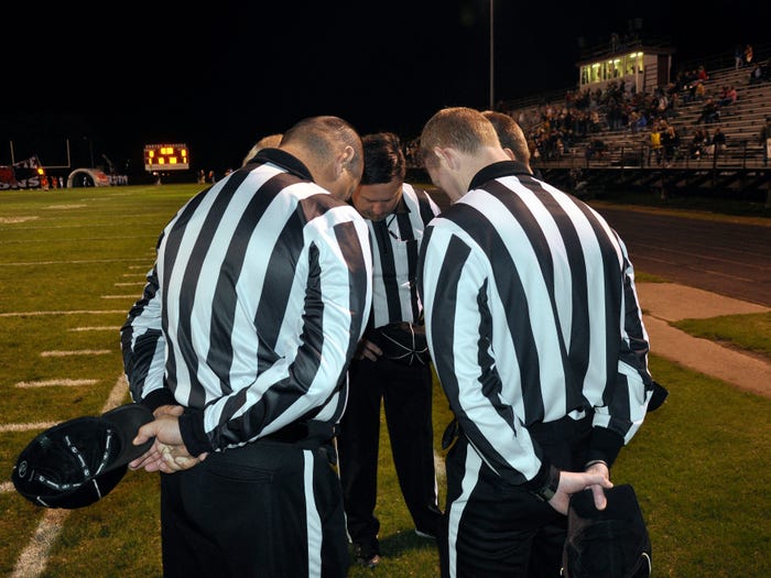 referees praying before high school football game