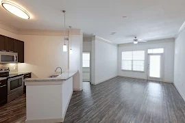 Apartment building living room and breakfast bar with wood-inspired flooring and neutral walls throughout 