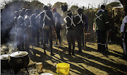 The initiate, in loincloth and their white cross-body beadwork, prepare to emerge from their seclusion boma on the Sunday morning. Also in the boma are the young men who have looked after them for the past three to four months.