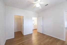 Bedroom with wood-inspired flooring, ceiling fan, walk-in closet, and neutral colored walls