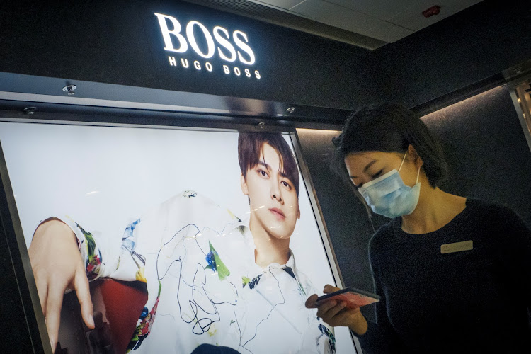 A woman walks past a store of German fashion house Hugo Boss in Beijing, China. Picture: REUTERS/THOMAS PETER/FILE