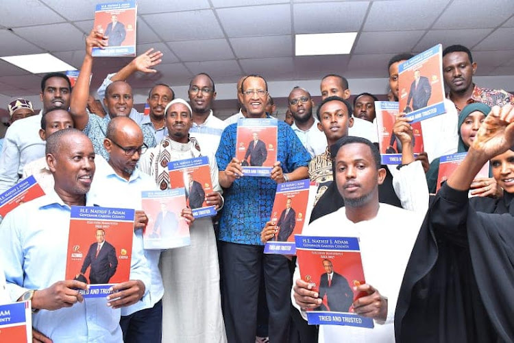 Former Garissa governor Nathif Jama with his supporters hold a booklet containing his 2022-2027 manifesto during the launch at a Garissa hotel on Saturday, July 23.