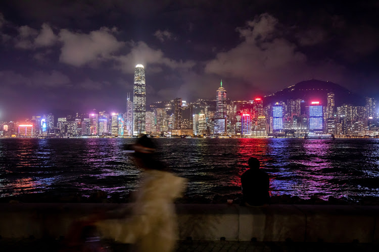 A pedestrian walks along a promenade in front of the city's skyline in Hong Kong, China, on Tuesday December 7 2021. Picture: BLOOMBERG/PAUL YEUNG