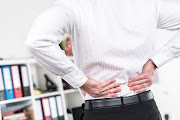 Man in formal clothing suffering from back pain at office.