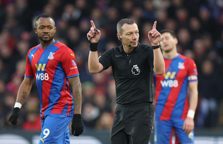 Referee Kevin Friend signals to look at the VAR monitor before awarding a penalty to Liverpool