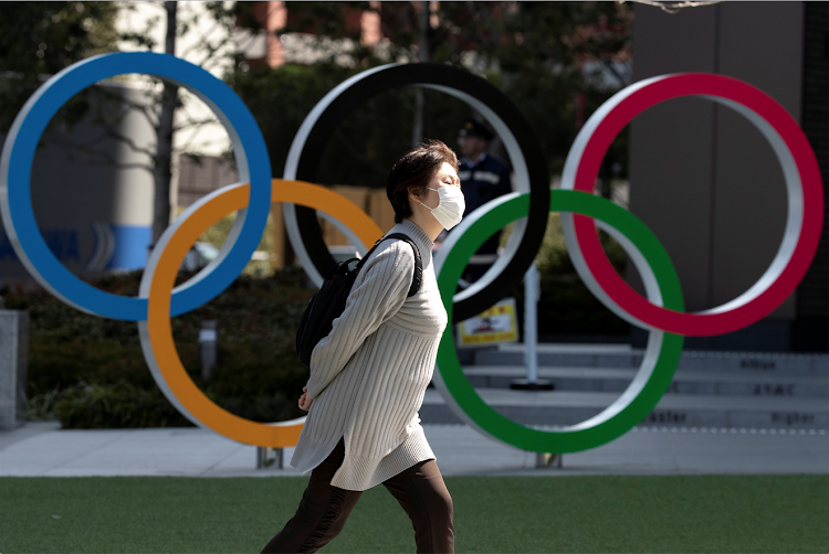 A woman wearing a protective face mask, following an outbreak of the coronavirus disease (COVID-19), walks past the Olympic rings in front of the Japan Olympics Museum in Tokyo, Japan March 13