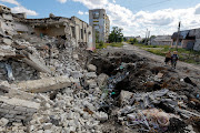 Local residents stand next to the debris of a destroyed building in the course of Russia-Ukraine conflict in Lysychansk, the city controlled by pro-Russian troops in the Luhansk region, Ukraine September 21, 2022. 