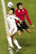 AERIAL DUEL: Norway's midfielder Ingvild Stensland, right, and China's forward Liu Sa, left, fight for the ball. Pic. Eugene Hoshiko. 23/09/07. © AP.