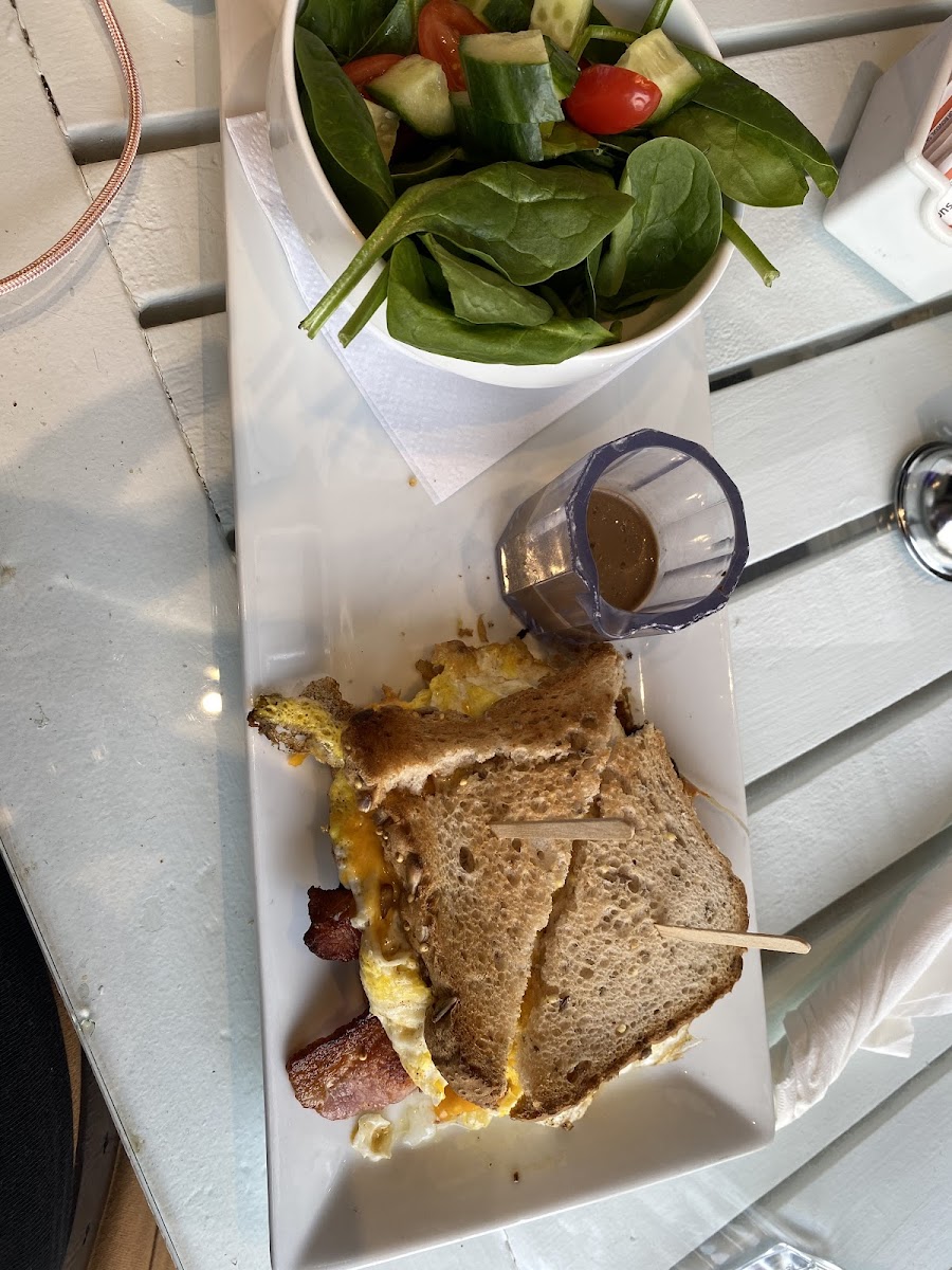 Breakfast sandwich (fried eggs, bacon, & cheese) on gluten free toast with a side salad