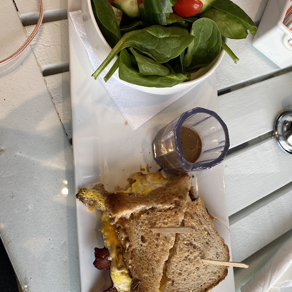 Breakfast sandwich (fried eggs, bacon, & cheese) on gluten free toast with a side salad