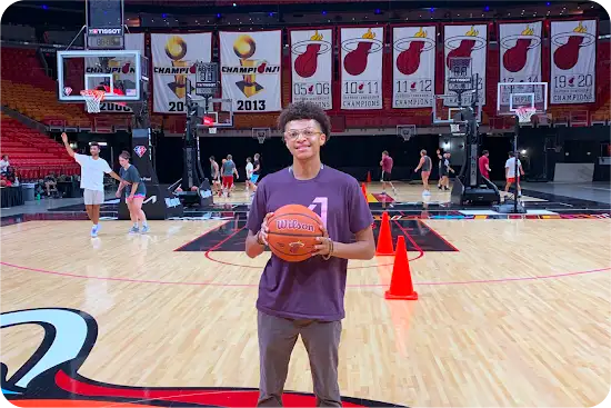 Khyri Lueben posing with basketball in front of Miami Heat court