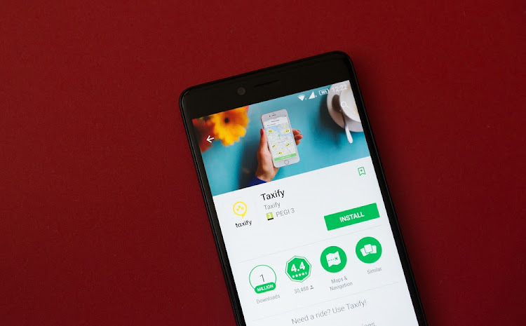 Smartphone with Taxify application in google play store on red background/