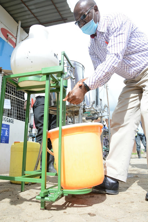 Trader Charles Kariuki Chawakah of Gilgil washes his hands at a point constructed by Giltec fabricators that automatically releases water and soap.