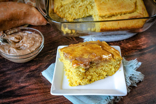 A slice of Sweet Potato Cornbread With Cinnamon Honey Butter on a plate.