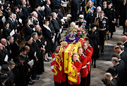 Members of the royal family follow behind the coffin of Queen Elizabeth II with the Imperial State Crown resting on top of it as it departs Westminster Abbey.