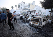 People inspect the area of Al-Ahli hospital where hundreds of Palestinians were killed in a blast that Israeli and Palestinian officials blamed on each other, and where Palestinians who fled their homes were sheltering amid the conflict with Israel, in Gaza City on October 18 2023.