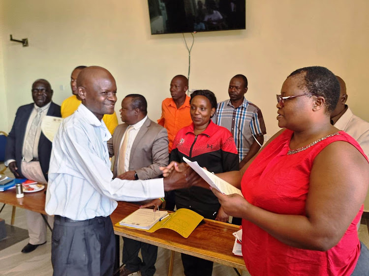 Kenya County Workers Union, Kakamega branch secretary Christine Songa (R) hands a reinstatement letter to one of the 47 revenue officers who were sacked by former Governor Wycliffe Oparanya on January 18