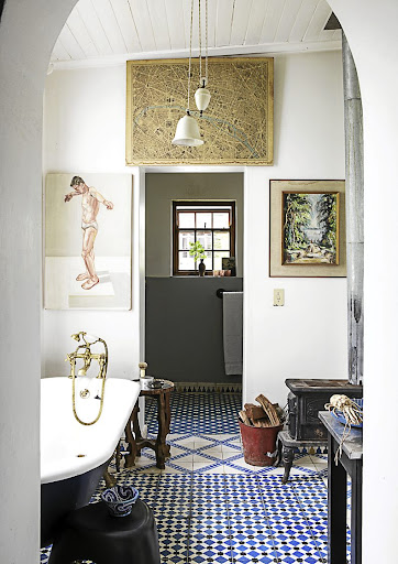 A trio of artworks frame the doorway in this eclectic bathroom.