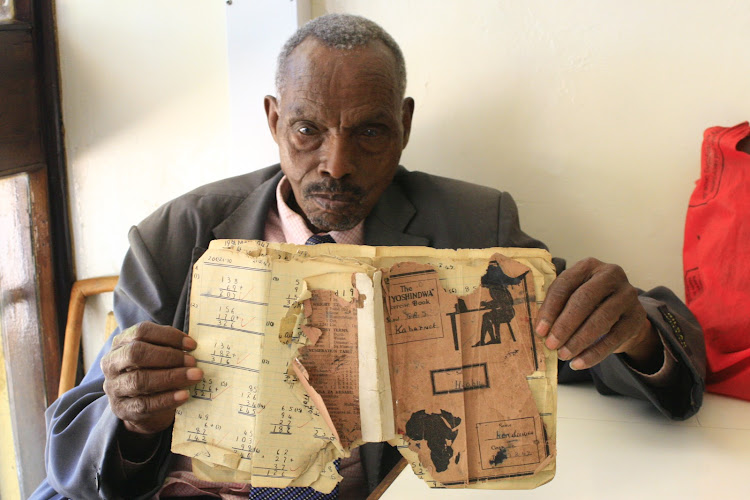 Mzee Simeon Kenduiwo, 89, displays an old exercise book on February 10, 2019. Moi taught him in 1947.