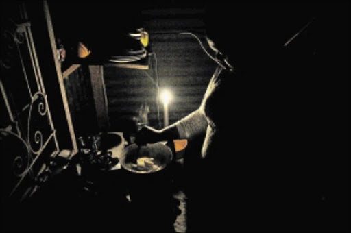 FED UP: A woman, who refused to be named, prepares a meal using a primus stove by candlelight during one of the nights Eskom rolled out load shedding in parts of Soweto. Many residents in the township accuse Eskom of overcharging them for direct electricity supply and yet they also reject prepaid metres PHOTO: Veli Nhlapo